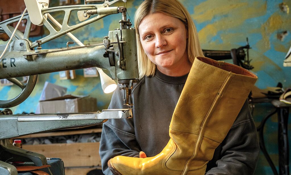 Schuhmacherin Karina Ranft in ihrer Werkstatt, sie hält einen gelben Stiefel in der Hand