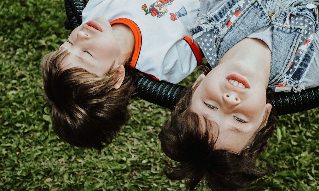 zwei Jungs liegen auf einer Art Hängematte, Perspektive: Köpfe von oben im Bild