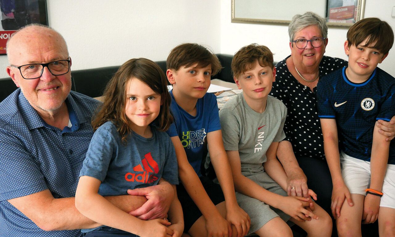 Gruppenbild: Oma und Opa mit einer Enkeltochter und drei Enkelsöhnen, im Hintergrund ein Ledersofa