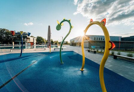 Blick über das Kinderbecken mit bunten Spielgeräten