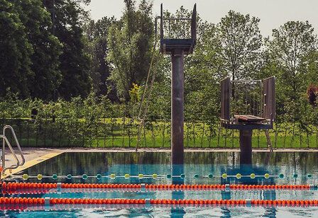 Blick über das Schwimmbecken auf zwei Sprungtürme