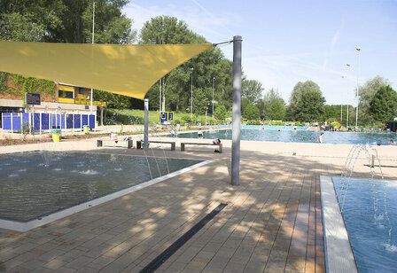 Blick über die Schwimmbecken mit Sonnensegel im Vordergrund