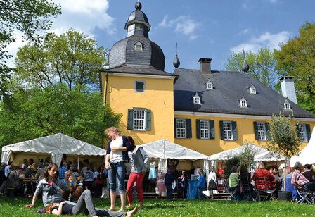 Außenansicht von Schloss Lüntenbeck, davor Pavillons und Leute