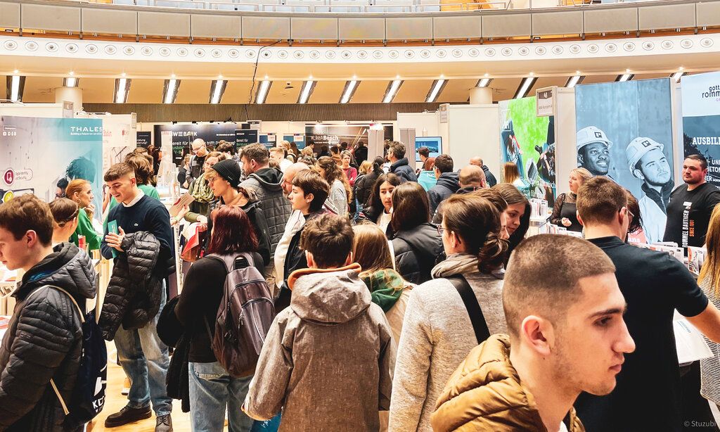 Viele Jugendliche bewegen sich durch eine Ausstellungshalle.