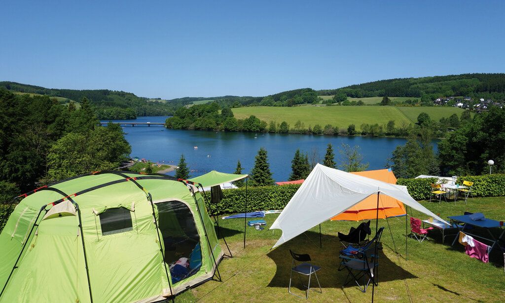 Zeltplatz mit mehreren Zelten an einem Seeufer, Wald und Wiese, im Sommer