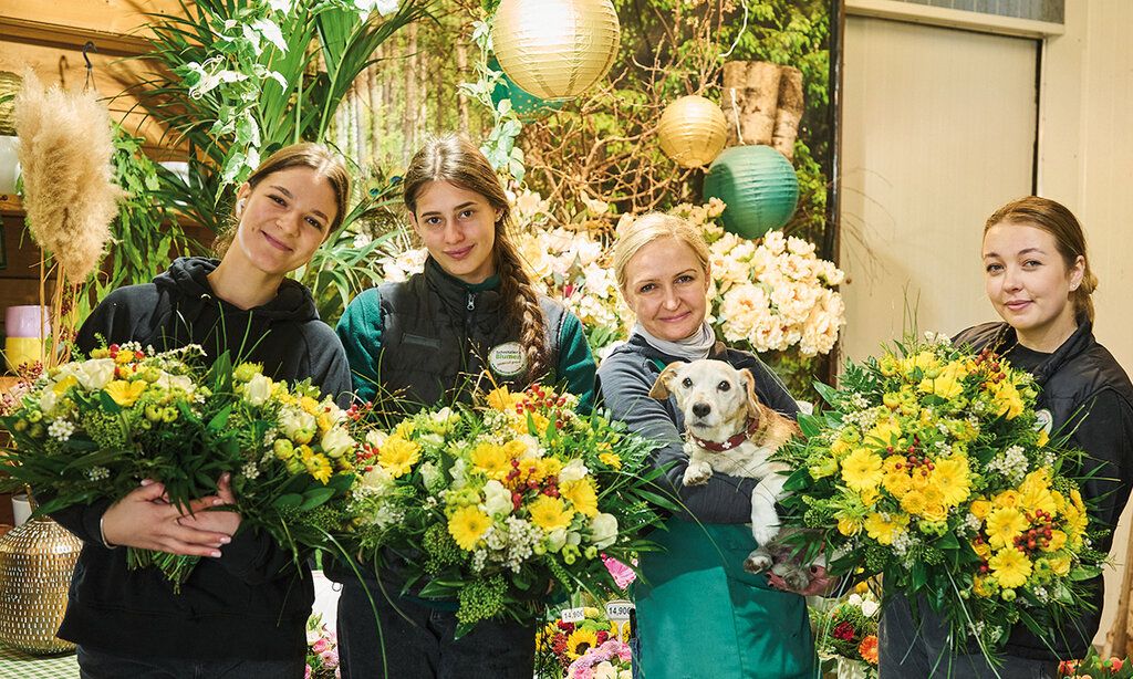 Vier Frauen mit Blumensträußen und ein Hund