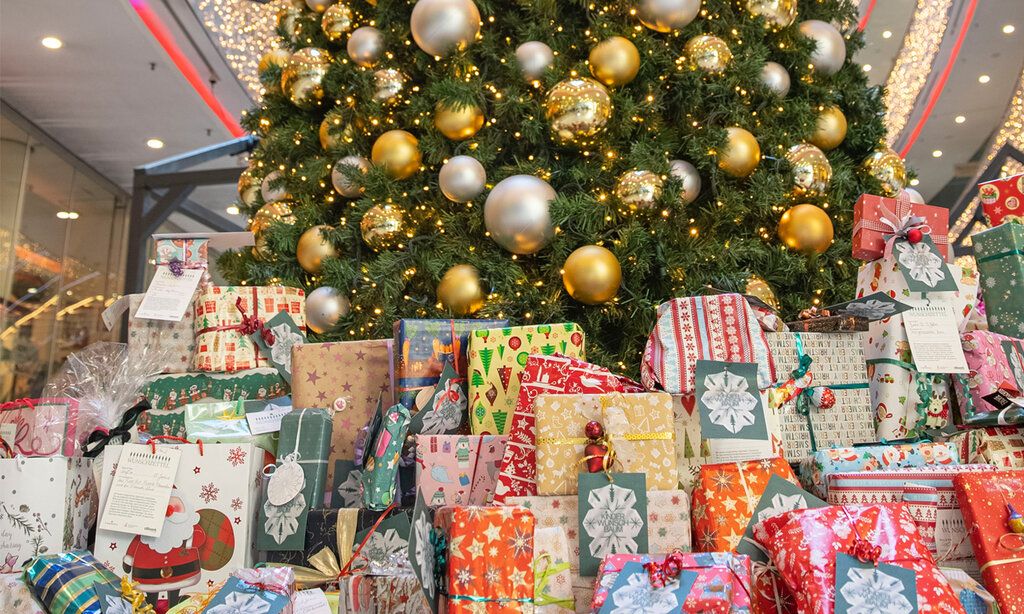 Viele bunte eingepackte Weihnachtsgeschenke liegen unter einem geschmückten Weihnachtsbaum