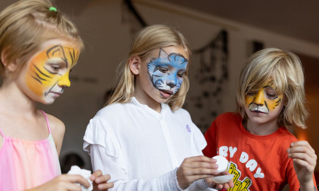 drei geschminkte Kinder basteln in den Räumen des Opernhauses