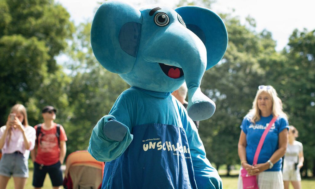 Blauer Elefant des Kinderschutzbundes im Park, im Hintergrund Leute