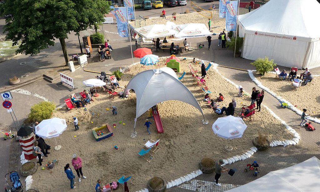 Veranstaltungsort, aufgeschütteter Sand, Pavillon, Zelt, Sonnenschirme Besucher von oben fotografiert