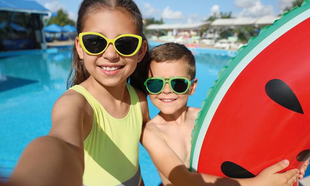 Ein Mädchen und ein Junge sind mit einem großen Schwimmreifen am Hotelpool