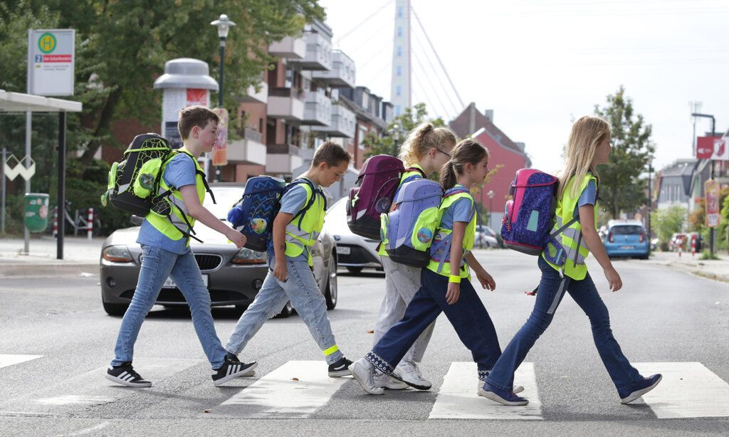 fünf Kinder gehen über einen Zebrastreifen in Düsseldorf, im Hintergrund Häuser und die Fleher Brücke