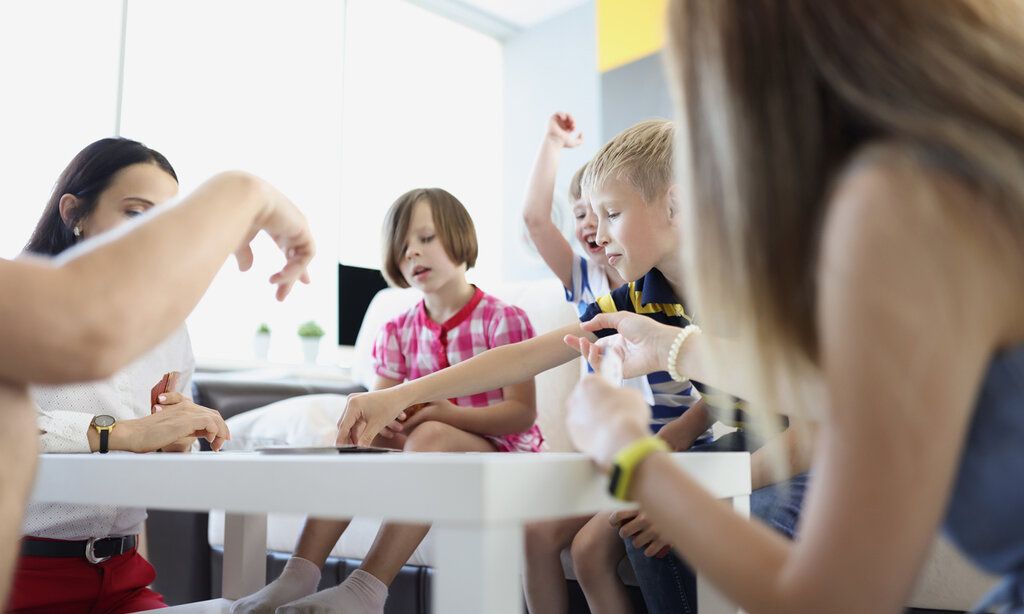 Kinder sitzen um einen Tisch herum und spielen ein Spiel