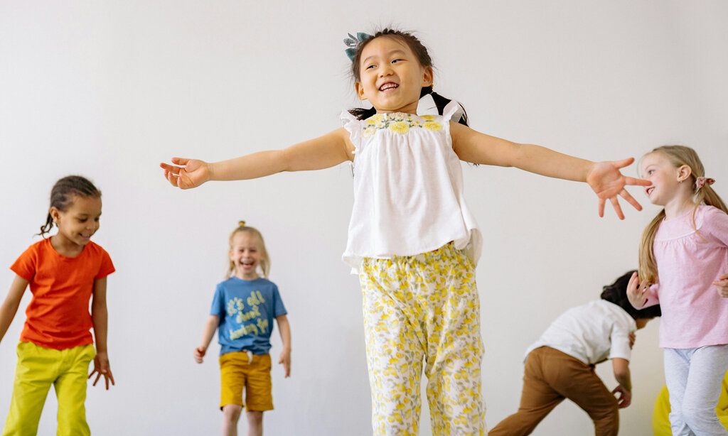 fünf Kinder bewegen sich mit Freude in einem Raum