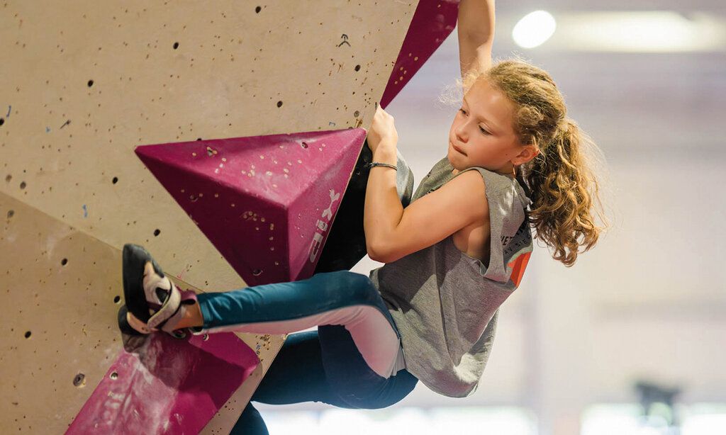 ein Mädchen klettert in einer Boulderhalle