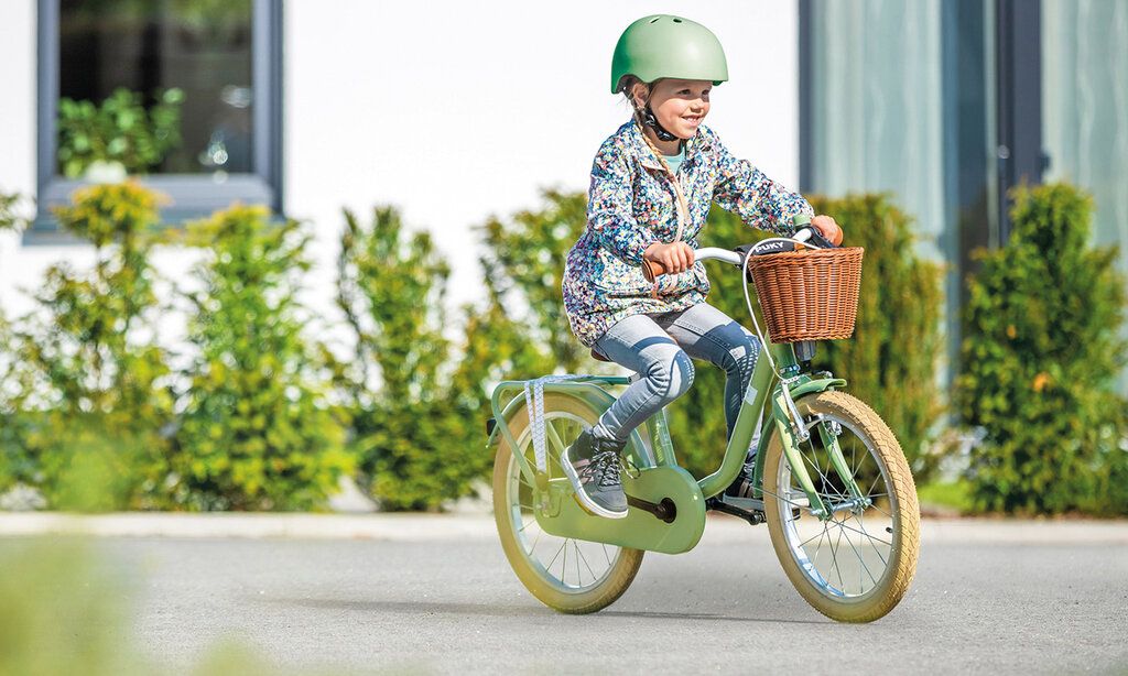 ein Mädchen mit Helm fährt auf einem Puky-Fahrrad