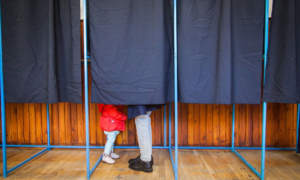 Menschen wählen in Wahlkabine mit Kind