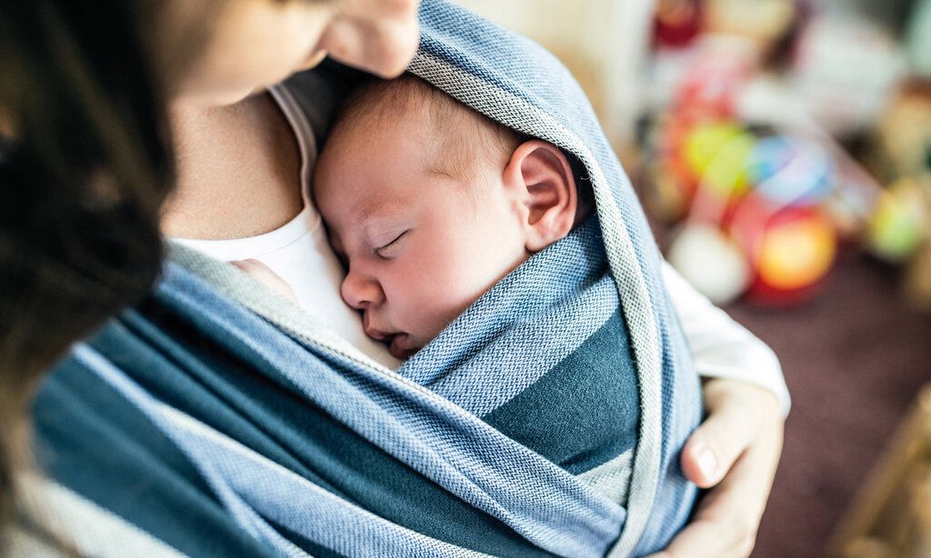 Mutter trägt ihr Baby im Tragetuch, Perspektive von oben, Hintergrund unscharf