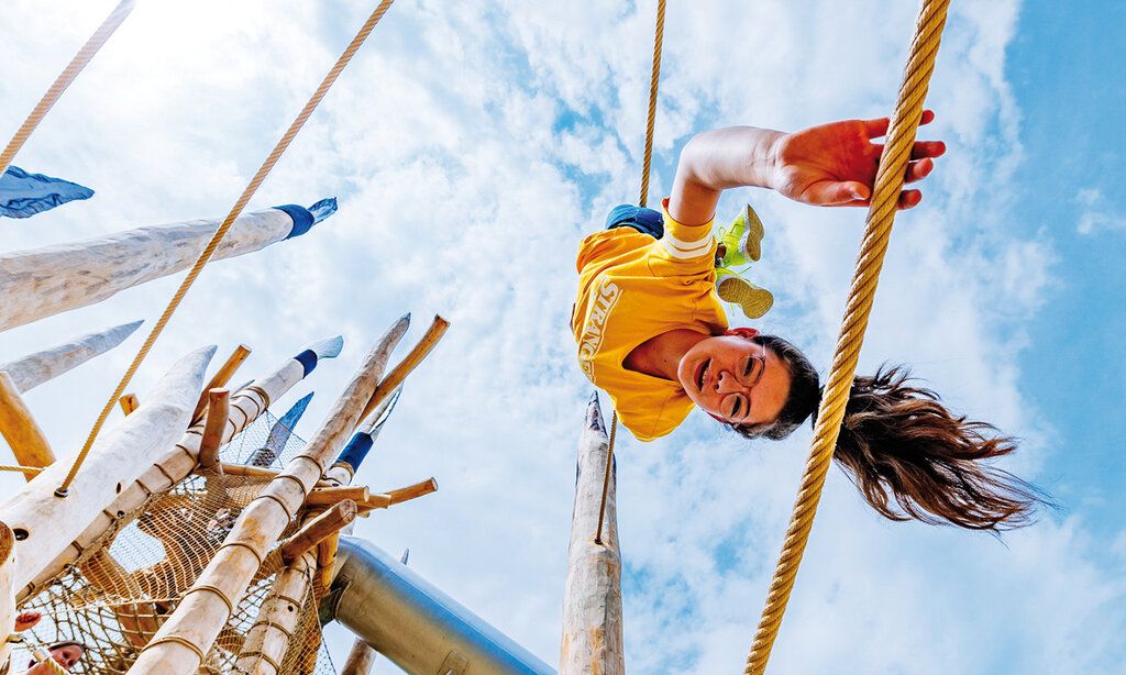 ein Mädchen turnt auf dem Spielplatz vom Neanderthal Museum herum, von unten betrachtet