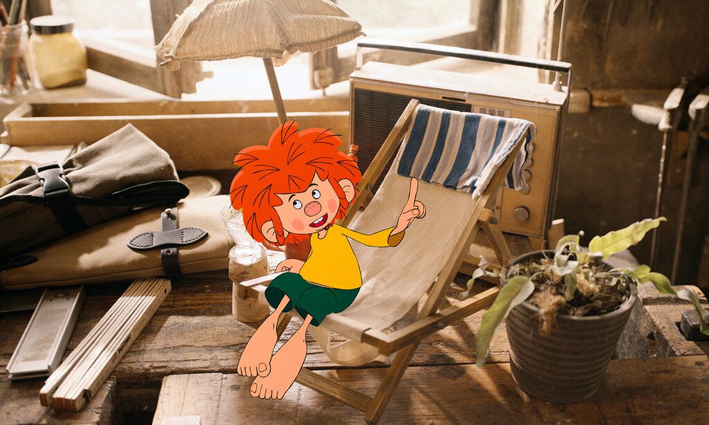 Zeichentrickfigur Pumuckl sitz auf einem kleinen Klapp-Liegestuhl in Meister Eders Werkstatt