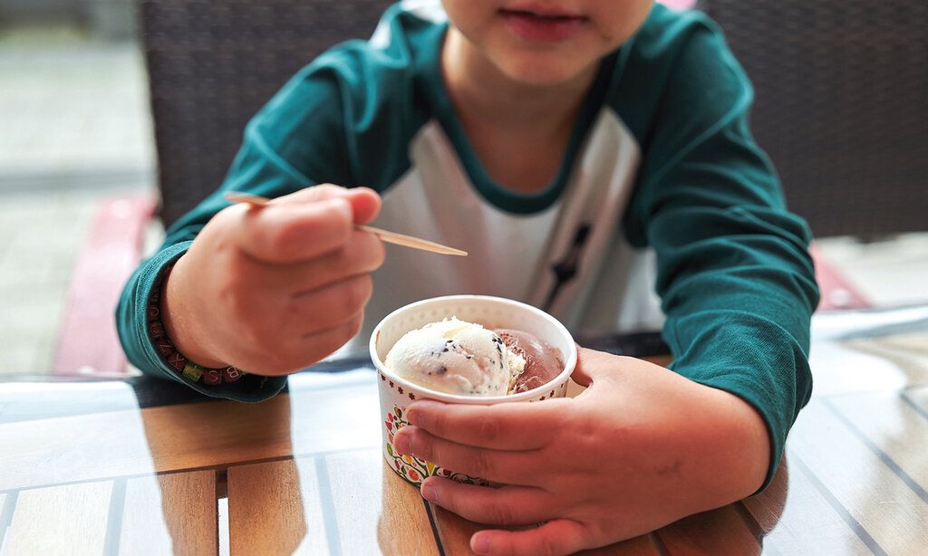 Kind mit Eisbecher im Eiscafé reo