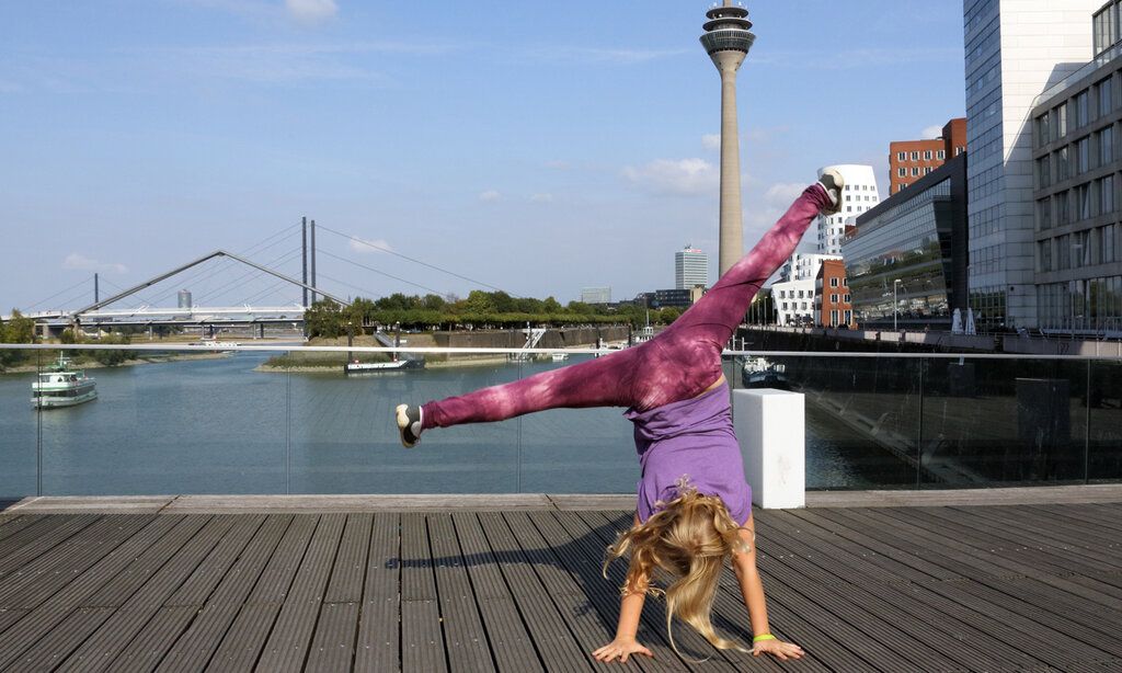 Mädchen, das einen Radschlag macht, im Hintergrund Medienhafen mit Fernsehturm