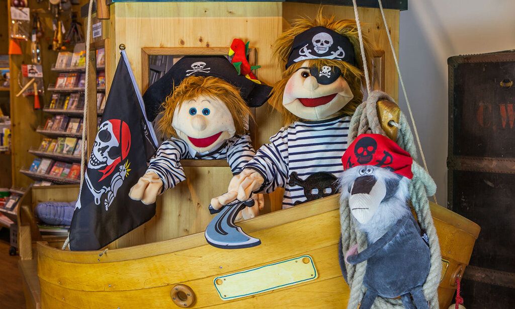 Zwei Piratenpuppen aus Stoff gucken aus einem Holz-Piratenschiff im Spielzeuggeschäft Spielschiff