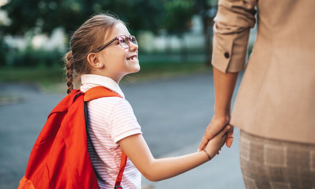 Tochter und Mutter gehen Hand in Hand, die Tochter schaut hoch zur Mutter, die ist aber nur im Anschnitt zu sehen