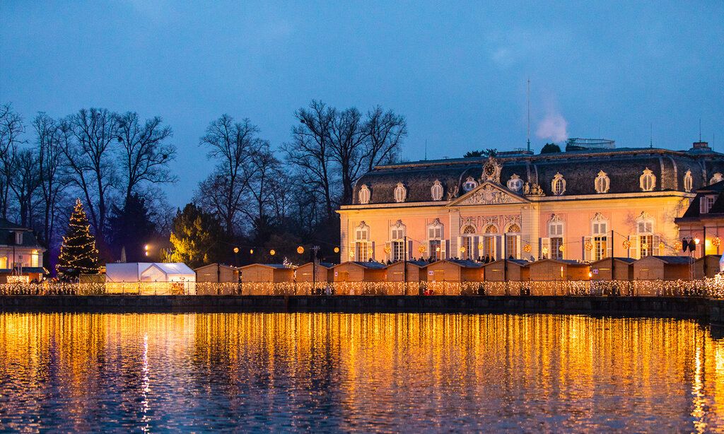 Weihnachtsmarkt vor dem Schloss Benrath am Abend, Lichterspiegelung im Wasser