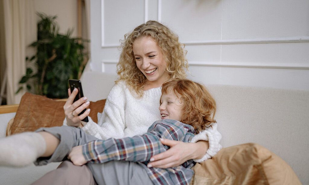 Mutter und Sohn auf dem Sofa schauen gemeinsam auf das Smartphone