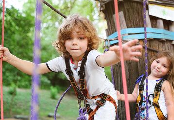 Zwei Kinder klettern in einem Hochseilgarten