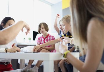 Kinder sitzen um einen Tisch herum und spielen ein Spiel