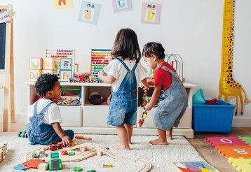 Drei Kleinkinder spielen in einem Kinderzimmer