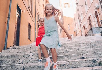 Zwei Mädchen laufen eine südländische Treppe hinab