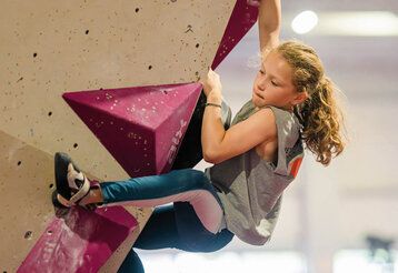 ein Mädchen klettert in einer Boulderhalle