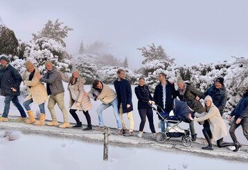 sehr viele Personen stehen hintereinander auf einer Straße, die nach oben führt, es liegt Schnee